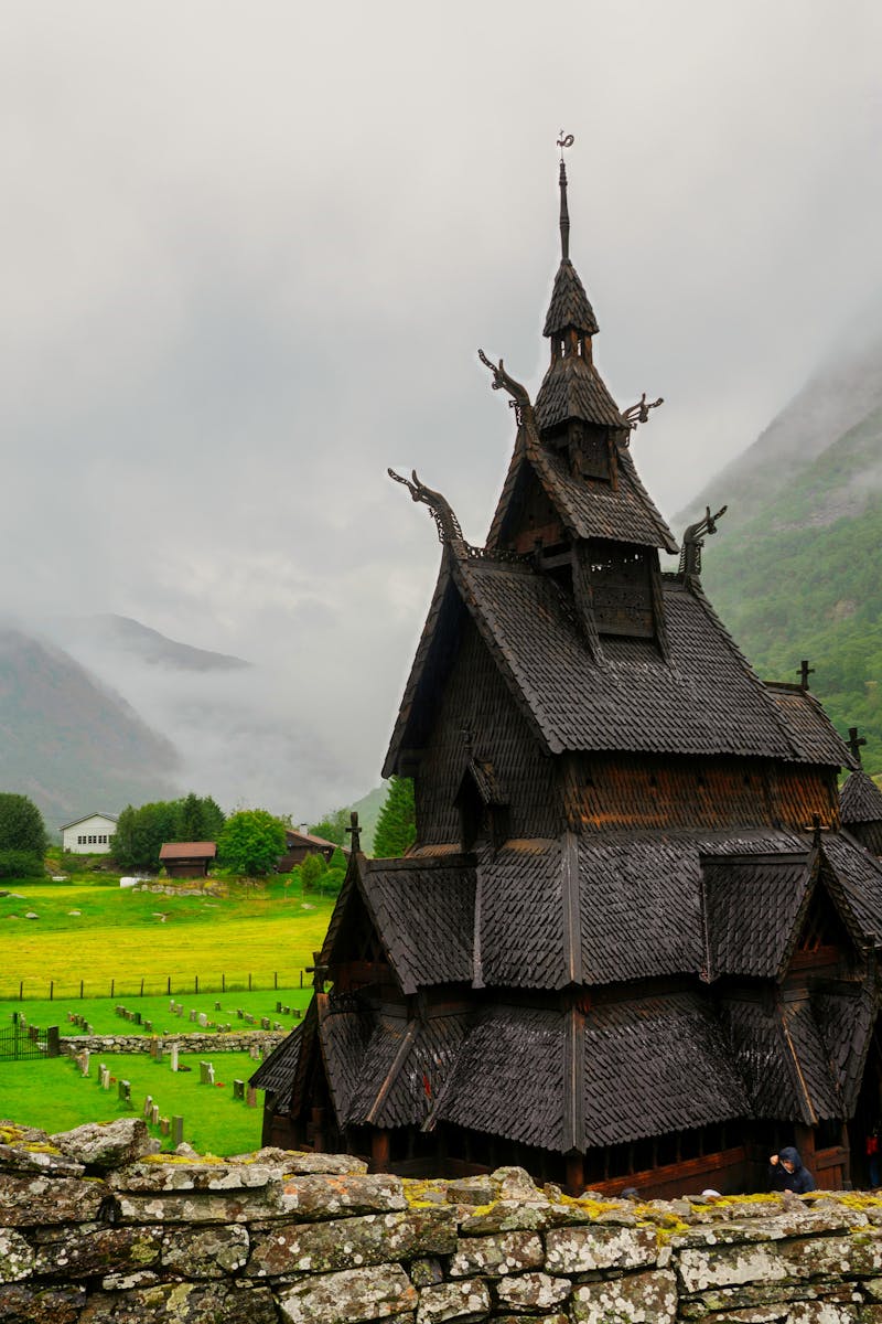 Borgund Stave Church with misty mountains and lush greenery in Vestland, Norway.