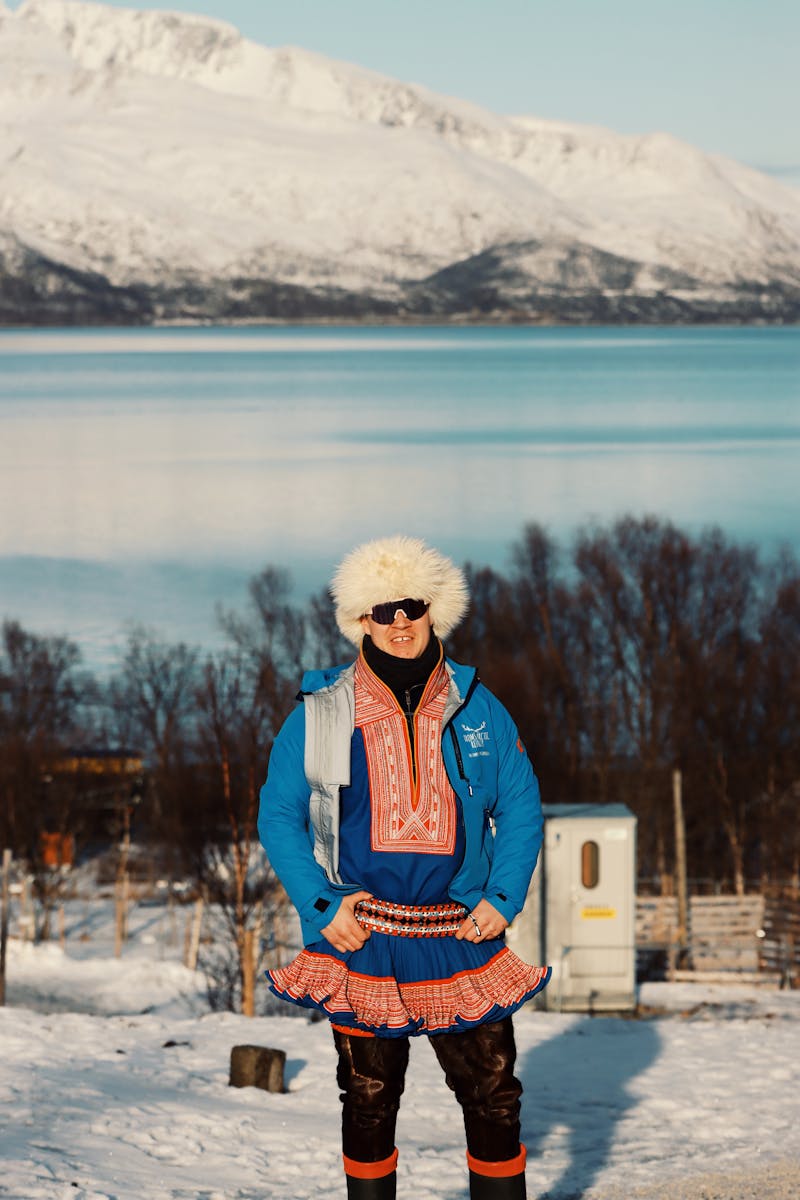 A person dressed in traditional winter clothing stands by the scenic Tromsø fjord in Norway.